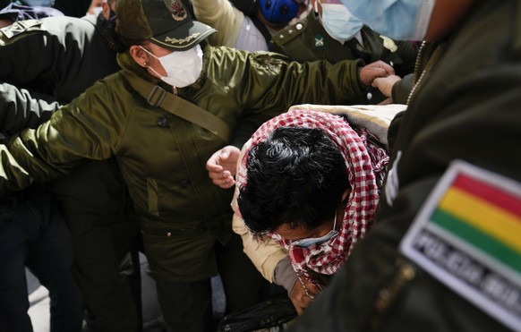 Max Mendoza is escorted in handcuffs by police to San Pedro jail in La Paz, Bolivia, Monday, May 23, 2022. The 52-year-old was detained and sent to jail on Monday after a judge ordered a six-month inv ...