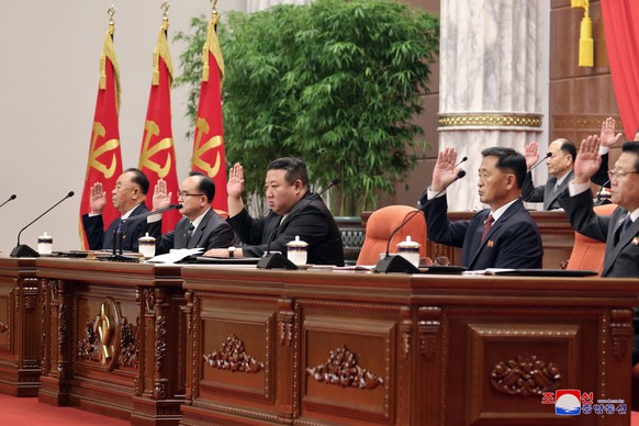 epa10699249 An undated photo released by the official North Korean Central News Agency (KCNA) shows North Korean leader Kim Jong Un (center) raising his hand with other officials as he holds a magnified…