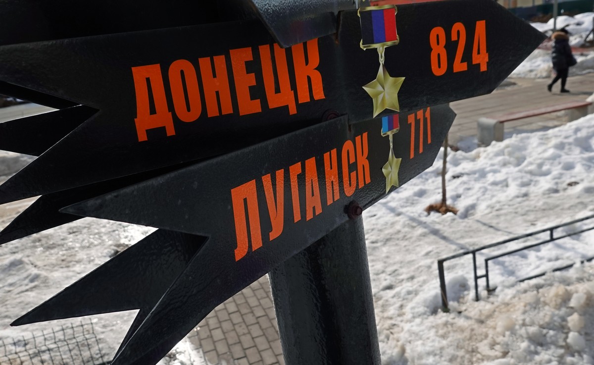 epa09831017 A woman walks past signs that show direction to different destinations, including the towns of Donetsk and Luhansk, as part of a so-called 'peoples monument to Russian soldier' c ...