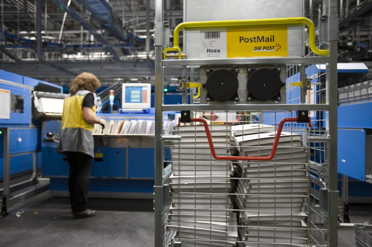 An employee of the Swiss Mail works at a sorting machine in the letter sorting center Muelligen in Zurich, Switzerland, pictured on March 14, 2008. A movable storage container with small parcels can b ...