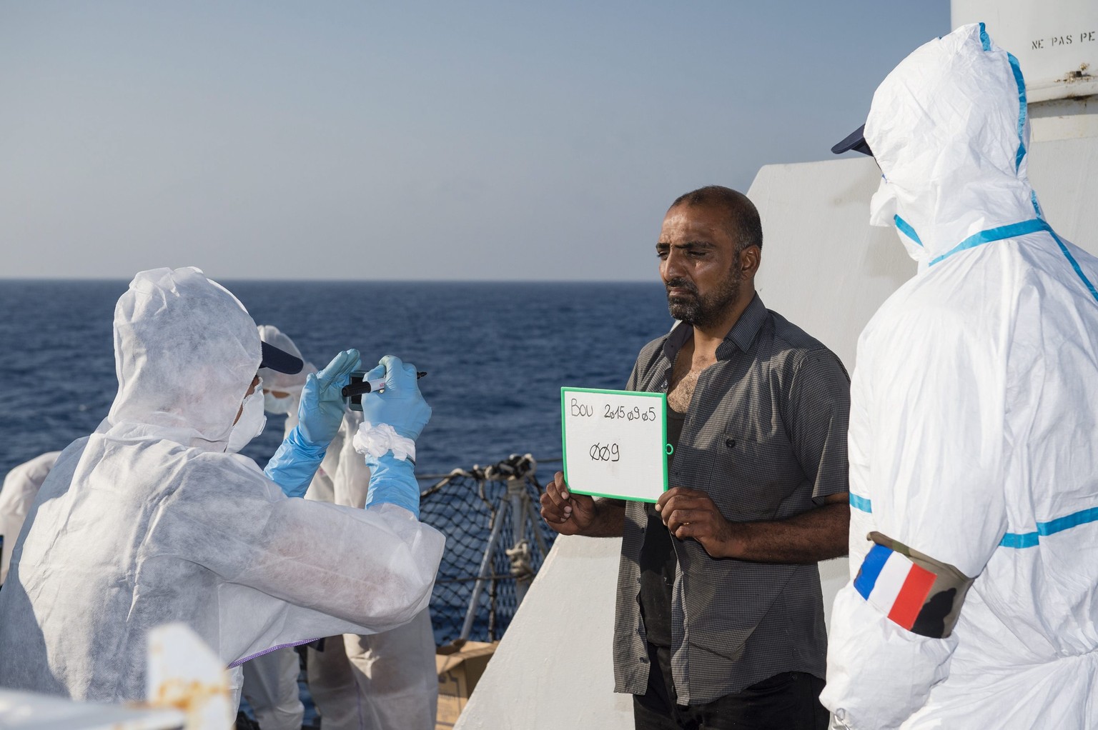 Mitglieder der französischen Marine registrieren auf dem Schiff Neuankömmlinge in Europa.