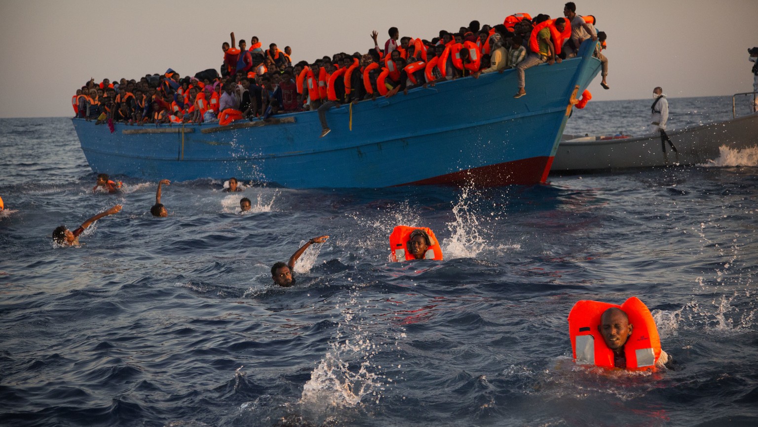 FILE - In this Monday, Aug. 29, 2016 file photo, men jumps onto the water from a crowded wooden boat during a rescue operation, on the Mediterranean sea, about 13 miles north of Sabratha, Libya. When  ...
