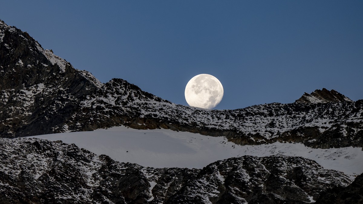 KEYPIX - La Pleine lune est visible au-dessus des montagnes valaisannes le jeudi 9 octobre 2025 a Saas-Fee. (KEYSTONE/Jean-Christophe Bott)