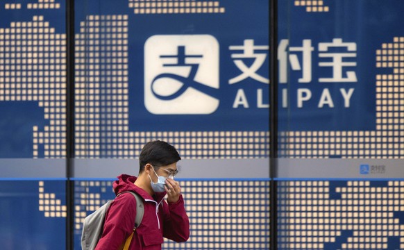 epa08921398 (FILE) - A man wearing a face mask walks past the Alipay logo on a building in Shanghai, China, 29 October 2020 (reissued 06 January 2021). On 05 January 2021 US President Donald Trump sig ...