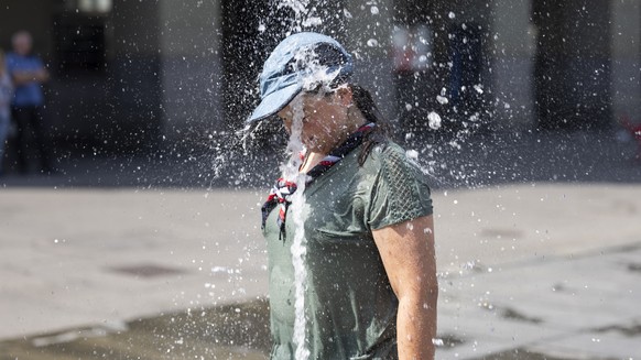 Eine Pfadfinderin aus Surrey, England, und ihre Kolleginnen und Kollegen der &quot;Surrey Scouts&quot; kuehlen sich beim Brunnen auf dem Bundesplatz ab, am Dienstag, 22. August, 2023 in Bern. Die Pfad ...
