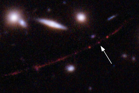 This image made available by NASA on Wednesday, March 30, 2022, shows the star Earendel, indicated by arrow, and the Sunrise Arc galaxy, stretching from lower left to upper right, optically bent due t ...