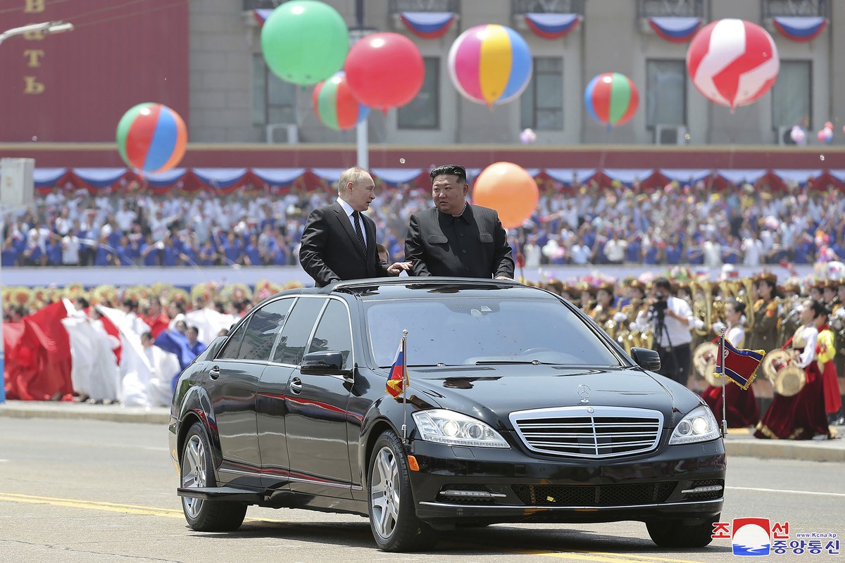 In this photo provided Thursday, June 20, 2024, by the North Korean government, Russian President Vladimir Putin, center left, and North Korea's leader Kim Jong Un, center right, ride on an open  ...