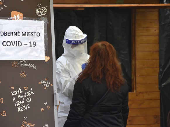Ein Mediziner in Schutzkleidung macht an einer Corona-Teststation einen Abstrich bei einer Frau. In der Slowakei werden die Corona-Massentests fortgesetzt. Foto: Miroslava Mlyn