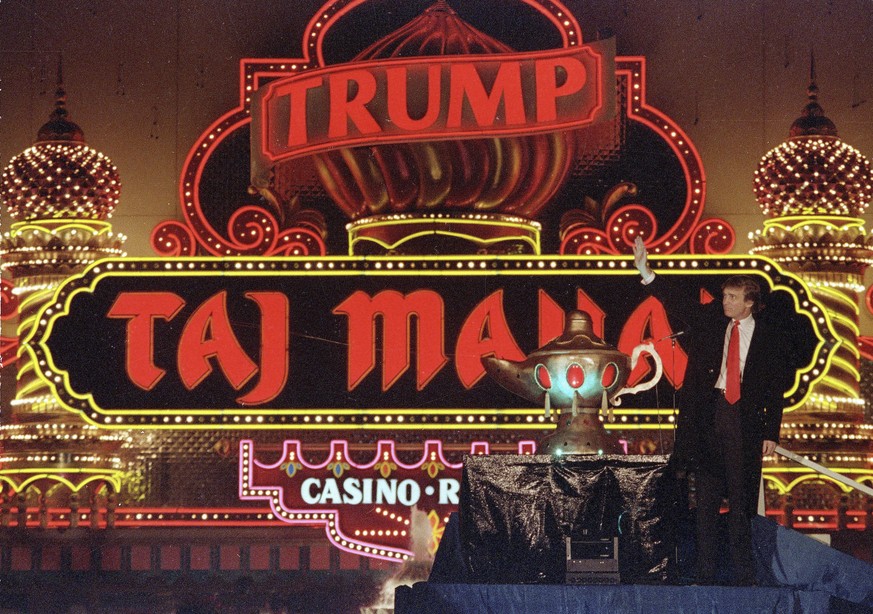 FILE - In this April 5, 1990 file photo, Donald Trump stands next to a genie's lamp as the lights of his Trump Taj Mahal Casino Resort light up during ceremonies to mark its opening in Atlantic City,  ...
