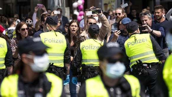 Corona-Gegner halten bei einer Demonstration den Polizisten ihre Handys ins Gesicht