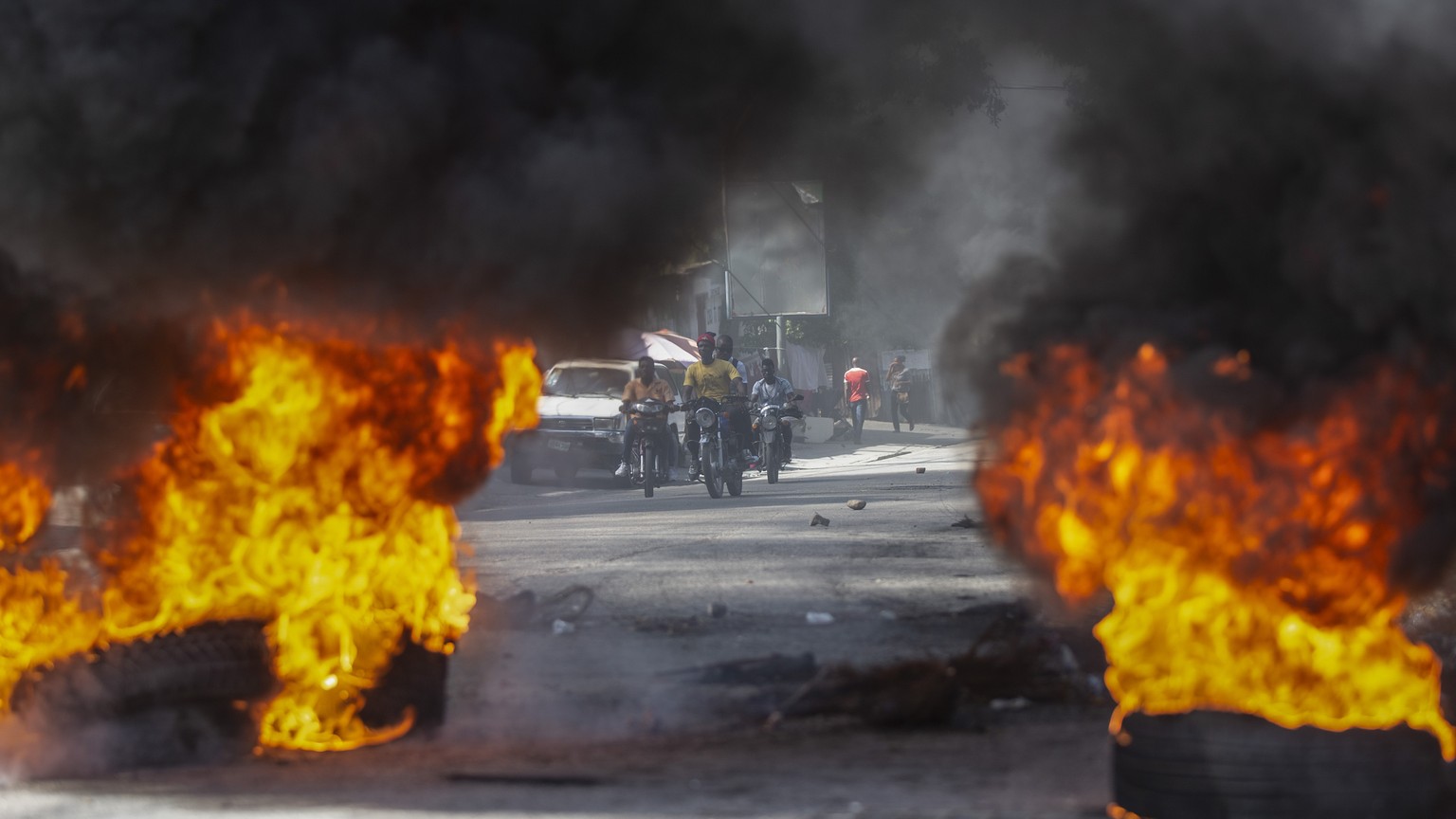 Taxi drivers run toward a barricade of burning tires set up by protesters demanding the release of kidnapped people, in Port-au-Prince, Haiti, Thursday, Nov. 25, 2021. The country is experiencing a ri ...