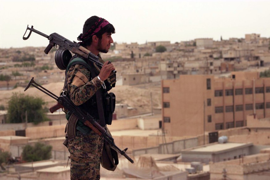 This Sunday, April 30, 2017 photo provided by the Syria Democratic Forces (SDF), shows a fighter from the SDF carrying weapons as he looks toward the northern town of Tabqa, Syria. U.S.-backed opposit ...