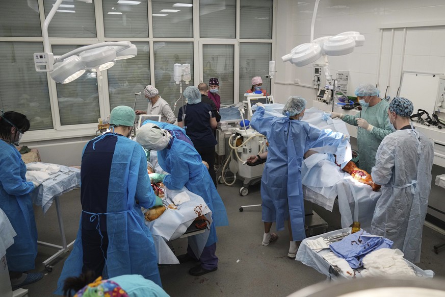 Medical workers operate on people injured by shelling in a residential area at a maternity hospital converted into a medical ward in Mariupol, Ukraine, Tuesday, March 1, 2022. Russian strikes on the k ...