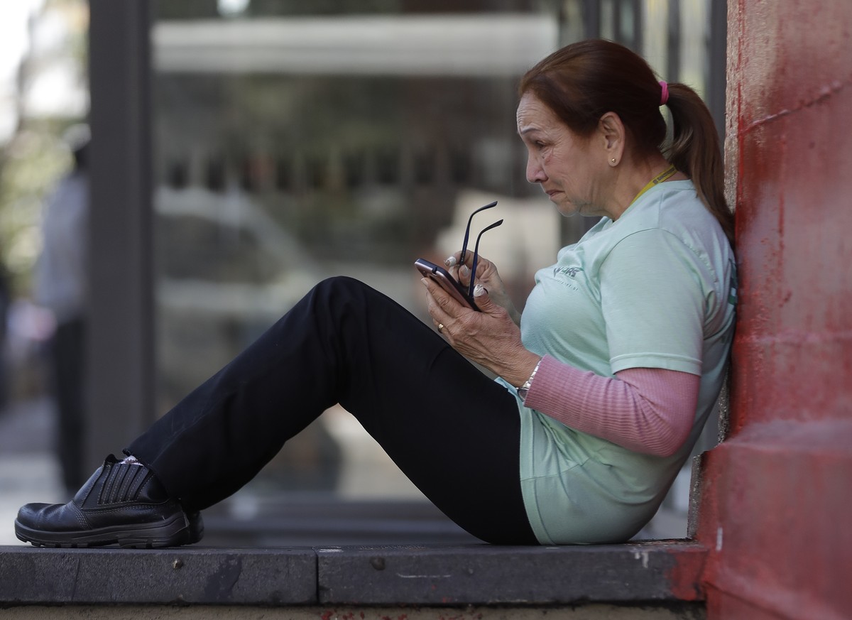 A women checks her mobile phone in Sao Paulo, Brazil, Tuesday, Aug. 28, 2018. A consortium of news organizations in Brazil is working to debunk rumors and misinformation circulating on WhatsApp, a wil ...