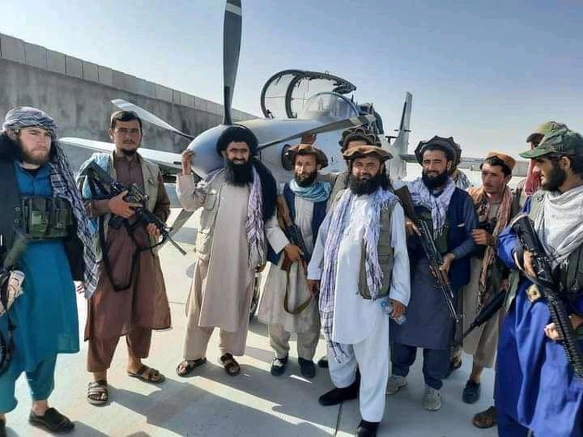 Des talibans posent devant un A-29B de construction américaine. Certains d'entre eux brandissent des fusils d'assaut fabriqués aux Etats-Unis.