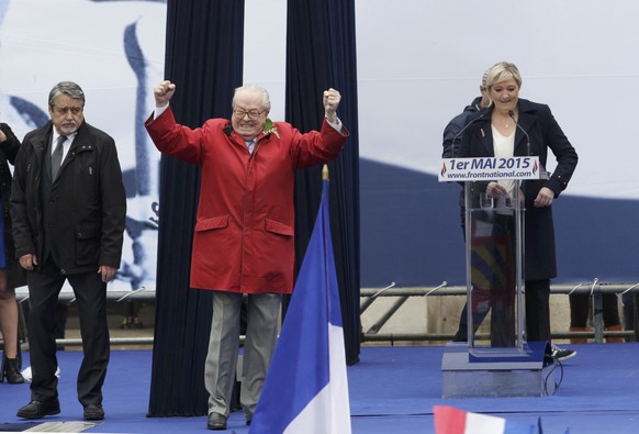 France&#039;s far-right National Front political party leader Marine Le Pen (R) watches as her father Jean-Marie Le Pen, party founder and honorary president, reacts on the podium at their traditional ...