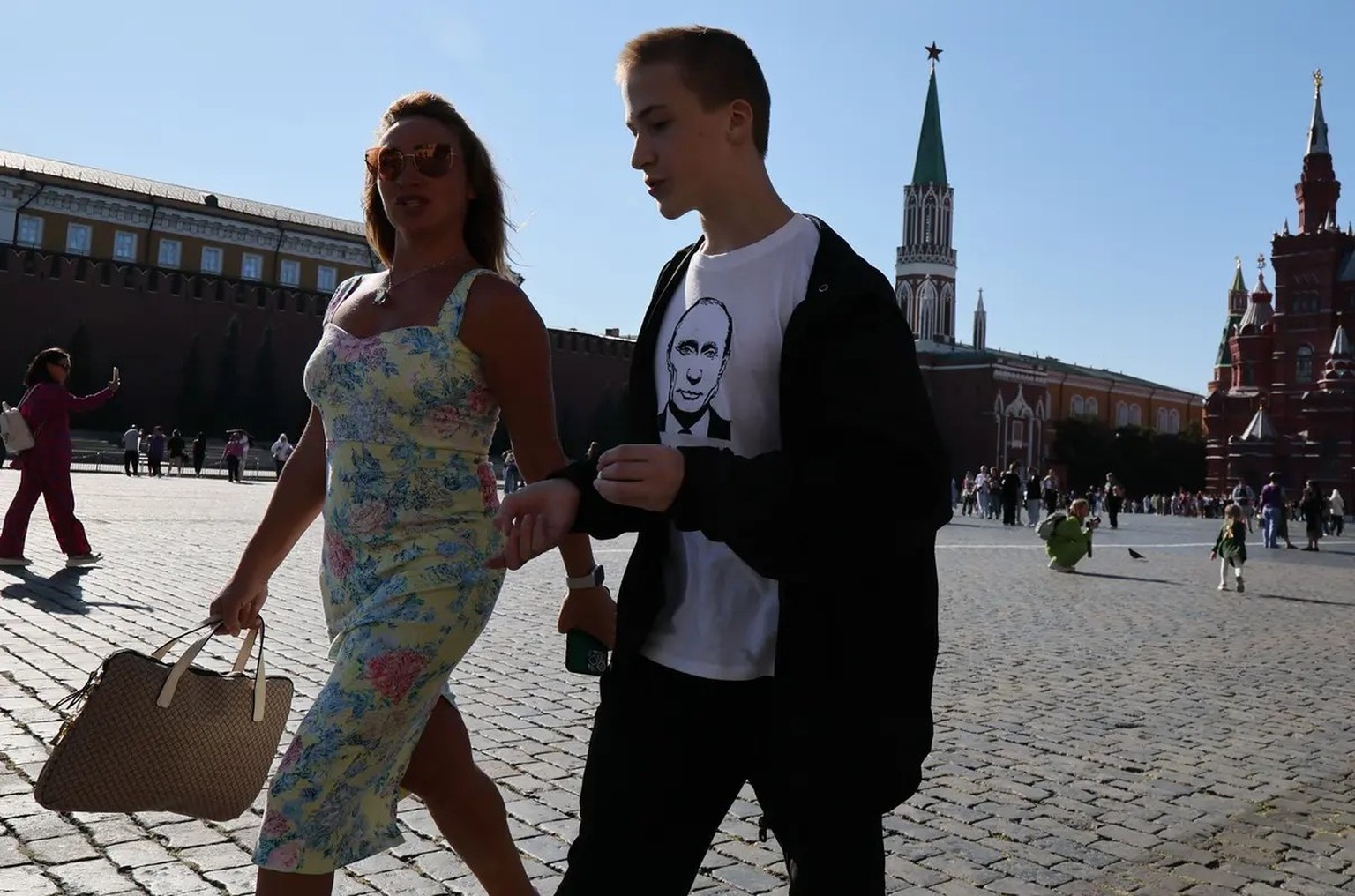 Ein junger Russe mit Putin-Shirt auf dem Roten Platz, neben ihm seine Begleiterin im Sommerkleid.