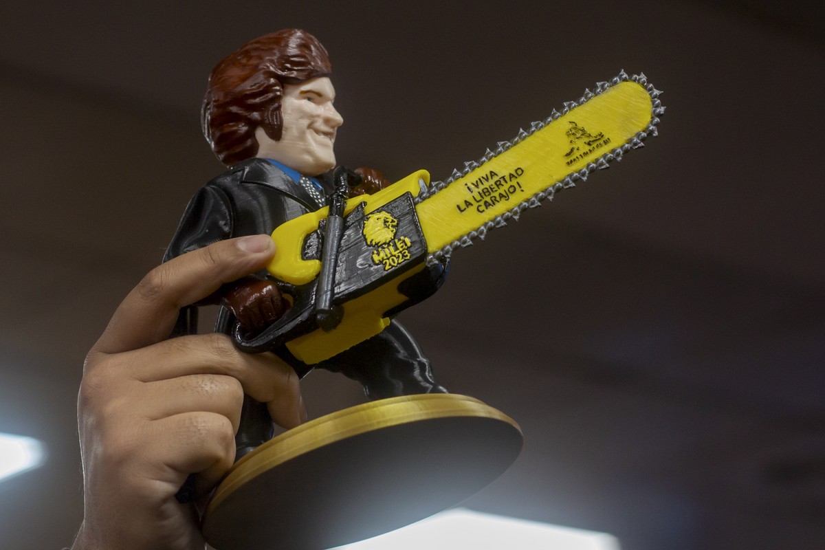 A supporter of presidential hopeful with the Liberty Advances coalition, Javier Milei, holds a statue of the candidate holding a chainsaw that reads in Spanish "Long live freedom!" while wai ...
