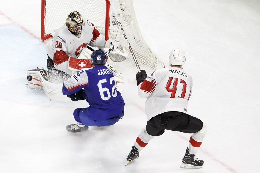 Switzerland&#039;s goaltender Reto Berra, left, saves a puck past Slovakia&#039;s defender Christian Jaros, center, and Switzerland&#039;s defender Mirco Mueller, right, during the IIHF 2018 World Cha ...