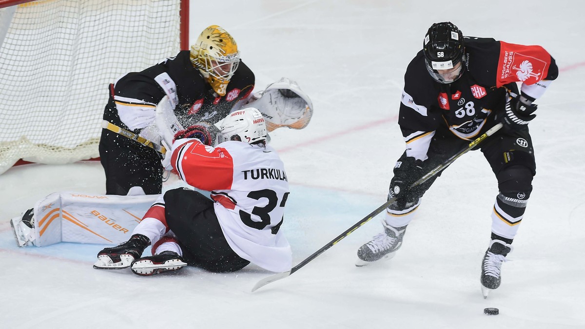 Luganos Goalkeeper Elvis Merzlikins, left, and Roman Loeffel, right, are fighting for the puck with JYP Jerry Turkulainen, middle, during the Champions Hockey League match between Switzerland's H ...