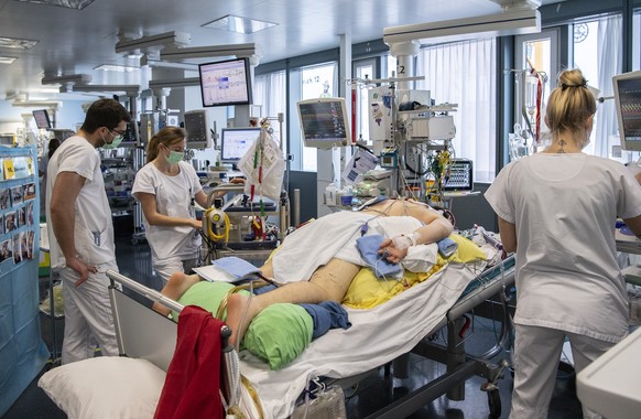 Pflegepersonal im Universitaetspital der Insel Gruppe kuemmern sich auf der Intensivstation um einen Covid Patienten , am Mittwoch, 16. Dezember 2020, in Bern. (KEYSTONE/Peter Schneider)