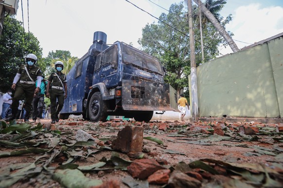 epa09863237 Armed Sri Lankan military personnel stand guard near the debris of vehicles torched during a protest against the current economic crisis, outside the President&#039;s private residence in  ...