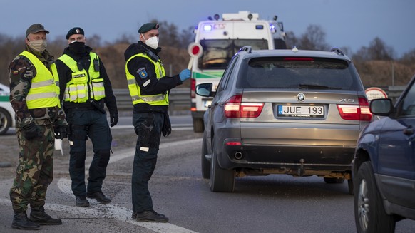 A policeman wearing a face mask to protect from coronavirus stops a car at a roadblock near Vilnius, Lithuania, Friday, April 10, 2020. The Lithuania government issued a movement order to the public r ...