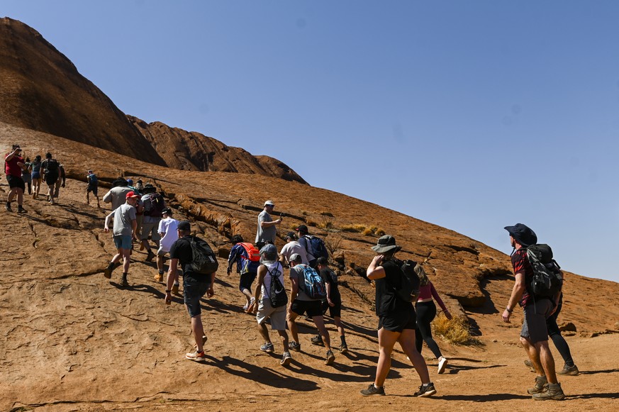 epa07948026 Tourists climb Uluru, Australia's iconic sandstone formation, in Uluru-Kata Tjuta National Park in Northern Territory, Australia, 25 October 2019. Tourists have been flocking to Uluru ...