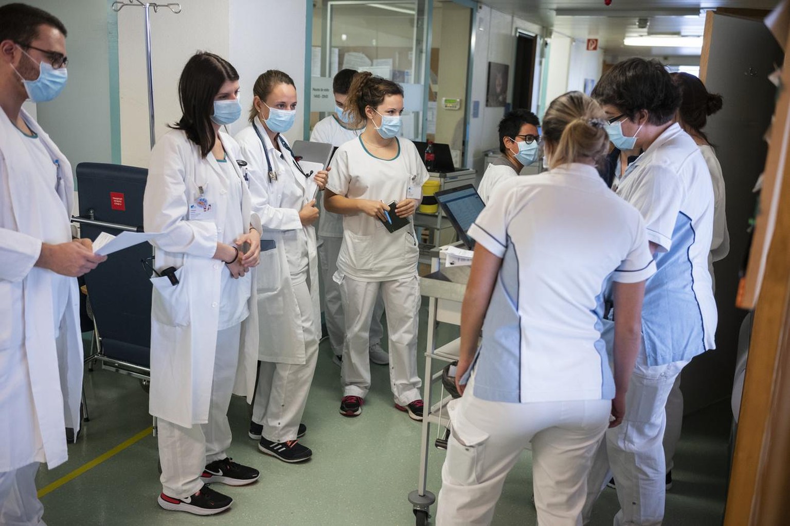 Aerztinnen und Pflegende besprichen sich in einem Huddle, der spezialisierten Kurzsitzung, ueber die anstehenden Patientenbesuche auf der Abteilung fuer COVID-Patienten im HFR Freiburg Kantonsspital,  ...