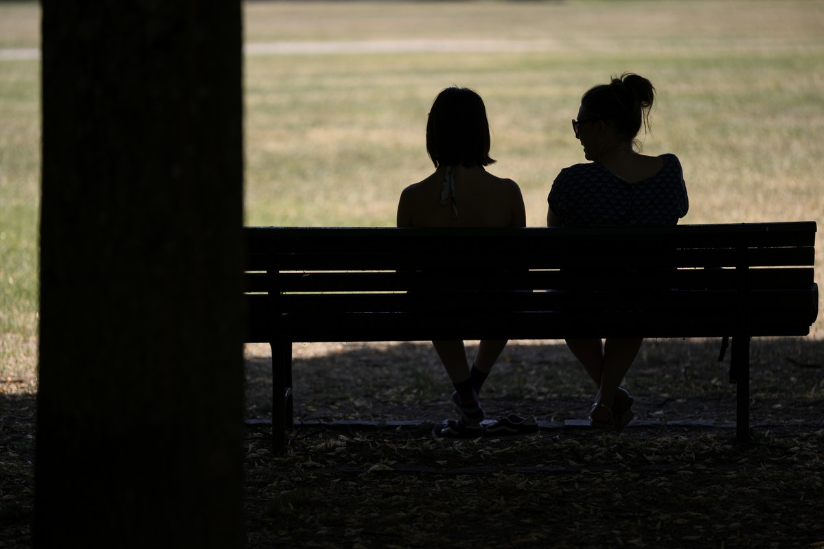 People are sitting on a bench in the shade in Milan Park during a heat wave in Lausanne, Switzerland, Tuesday, June 23, 2026. A heat wave is hitting Switzerland and is expected to last at least until  ...
