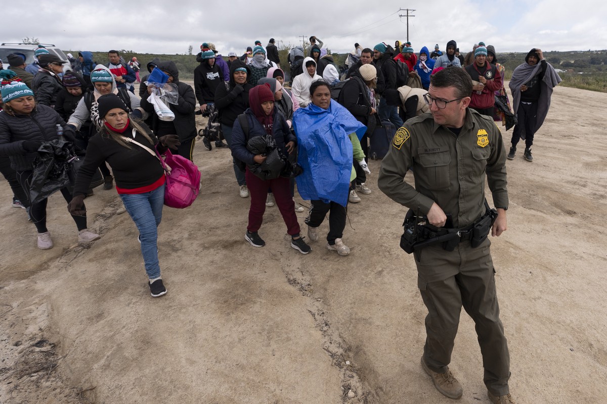 FILE - People seeking asylum, including a group from Peru, walk behind a Border Patrol agent towards a van to be processed after crossing the border with Mexico nearby, on April 25, 2024, in Boulevard ...