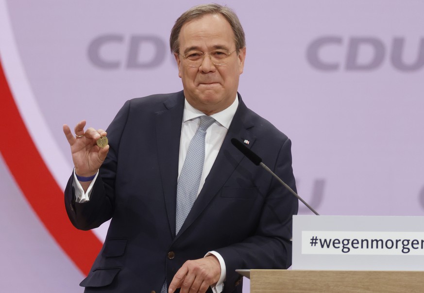 North Rhine-Westphalia&#039;s Governor and candidate as leader of the Christian Democratic Union (CDU) Armin Laschet shows a luck coin offered to him by his father as he delivers his speech on the sec ...