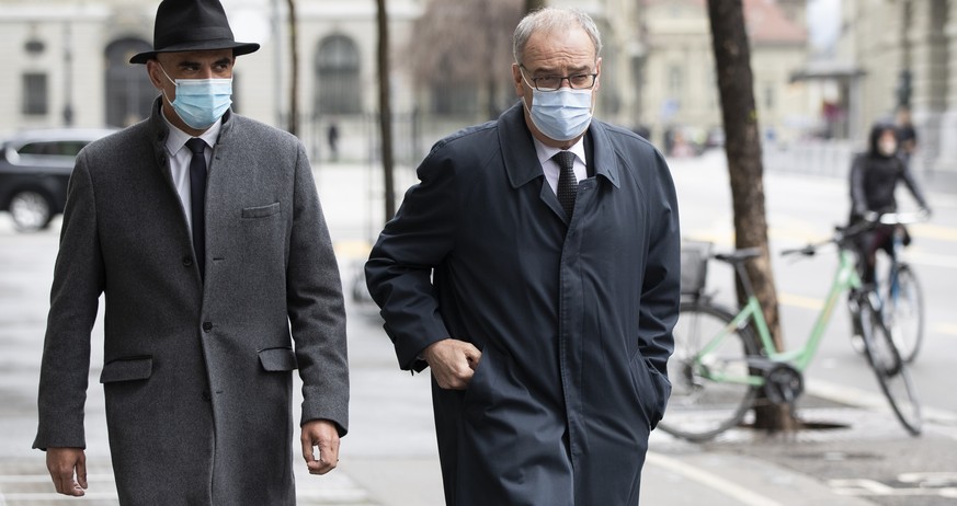 Bundespraesident Guy Parmelin, rechts, und Bundesrat Alain Berset auf dem Weg zu einer Medienkonferenz ueber das Covid-19-Gesetz, am Montag, 12. April 2021, in Bern. (KEYSTONE/Peter Klaunzer)