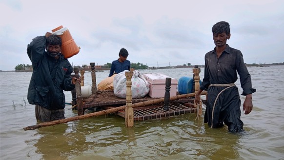 People use a cart to salvage usable items from their flood-hit homes while they cross a flooded area to reach in higher location, in Tando Jan Muhammad, in southern Pakistan, Wednesday, Heavy rains ha ...