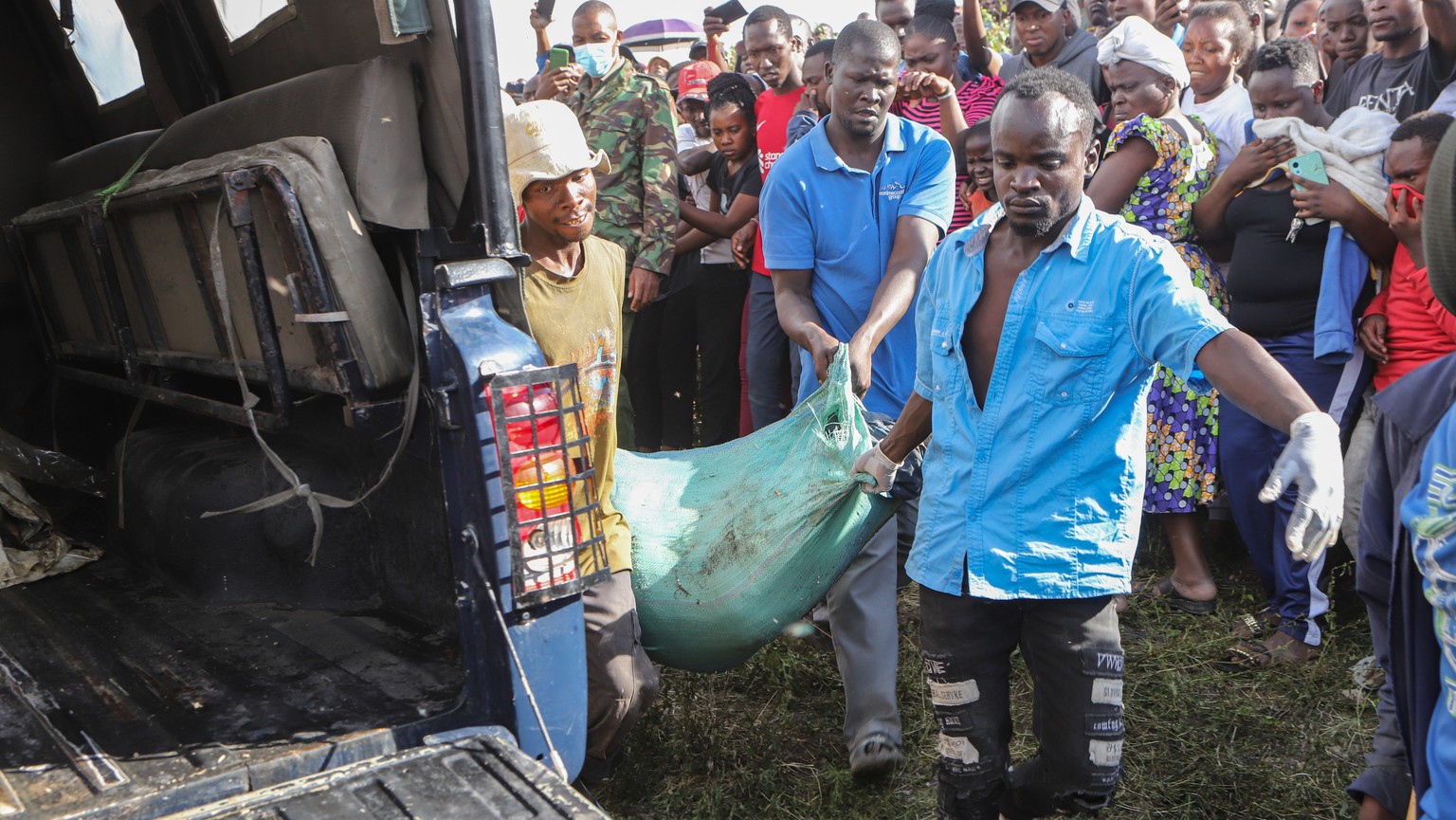 epa11474603 A group of men carries a body wrapped in a bag retrieved from inside a quarry turned into a dump site at Embakasi area in Nairobi, Kenya, 12 July 2024. Police stated that six severely muti ...