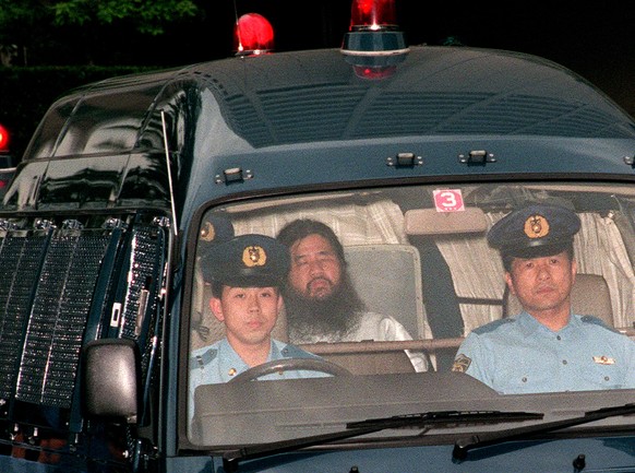 epa06866854 (FILE) - A file photo taken on 16 June 1995 , shows cult Aum Shinrikyo founder Shoko Asahara (C), born Chizuo Matsumoto, being escorted by police to the Tokyo Metropolitan Police Departmen ...