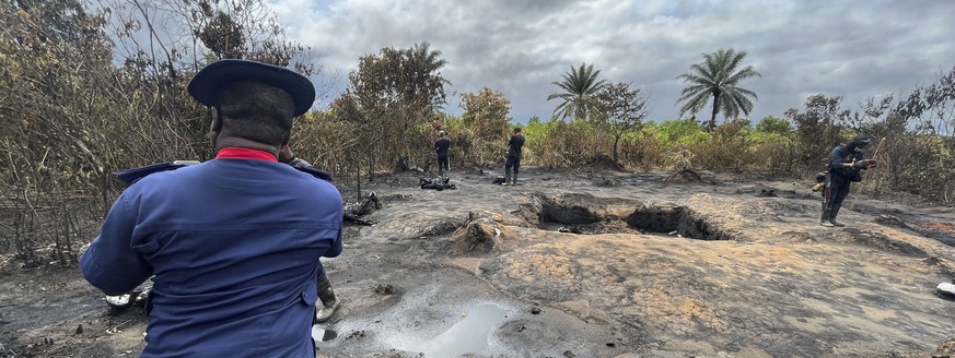 EDS NOTE: GRAPHIC CONTENT - - A security officer looks at charred bodies of victims of an illegal refinery explosion in Emohua, Niger Delta Nigeria Tuesday, Oct. 3, 2023. At least 15 people have been  ...
