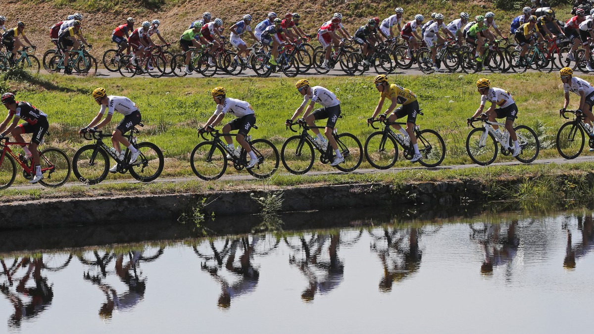 FILE - In this July 5, 2017 file photo, the pack with Britain's Geraint Thomas, wearing the overall leader's yellow jersey, is reflected in a pond during the fifth stage of the Tour de Franc ...
