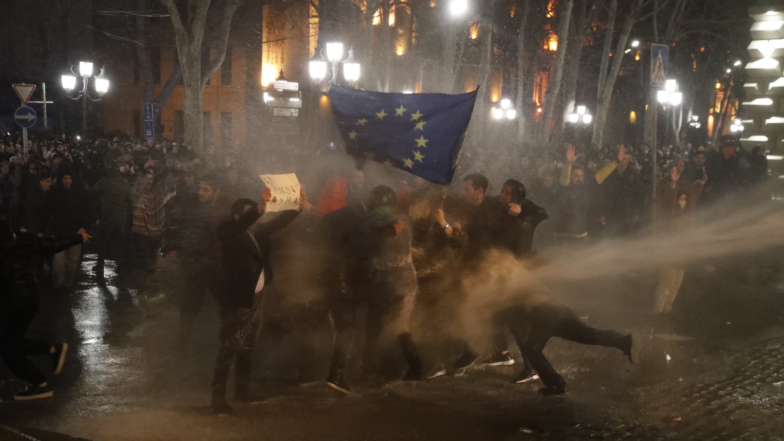 epa10508135 Police use a water cannon to disperse protesters holding an EU flag during a demonstration against the passing of the so-called 'Foreign Agents Law' in front of the parliament building in ...