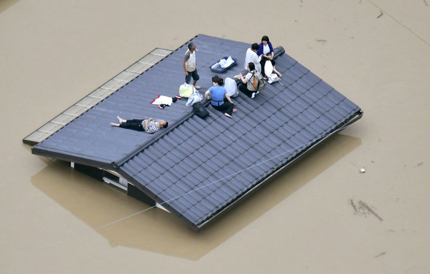 People waif to be rescued on the top of a house almost submerged in floodwaters caused by heavy rains in Kurashiki, Okayama prefecture, southwestern Japan, Saturday, July 7, 2018. Torrents of rainfall ...