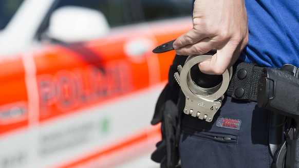 Ein Beamter der Kantonspolizei St. Gallen greift zu Handschellen. (Symbolbild)