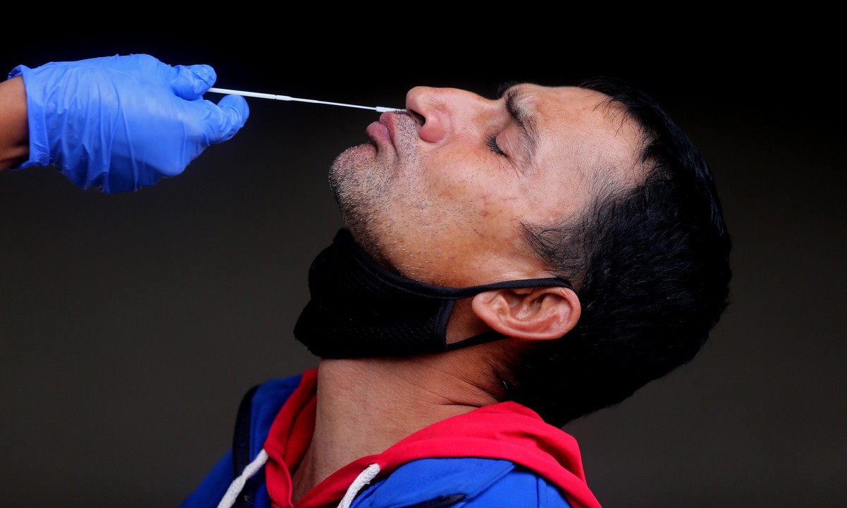 epaselect epa09610912 A health worker takes a nasal sample of a man for a COVID-19 test at city railway station, in Bangalore, India, 29 November 2021. The Karnataka State Government is urging a ban o ...