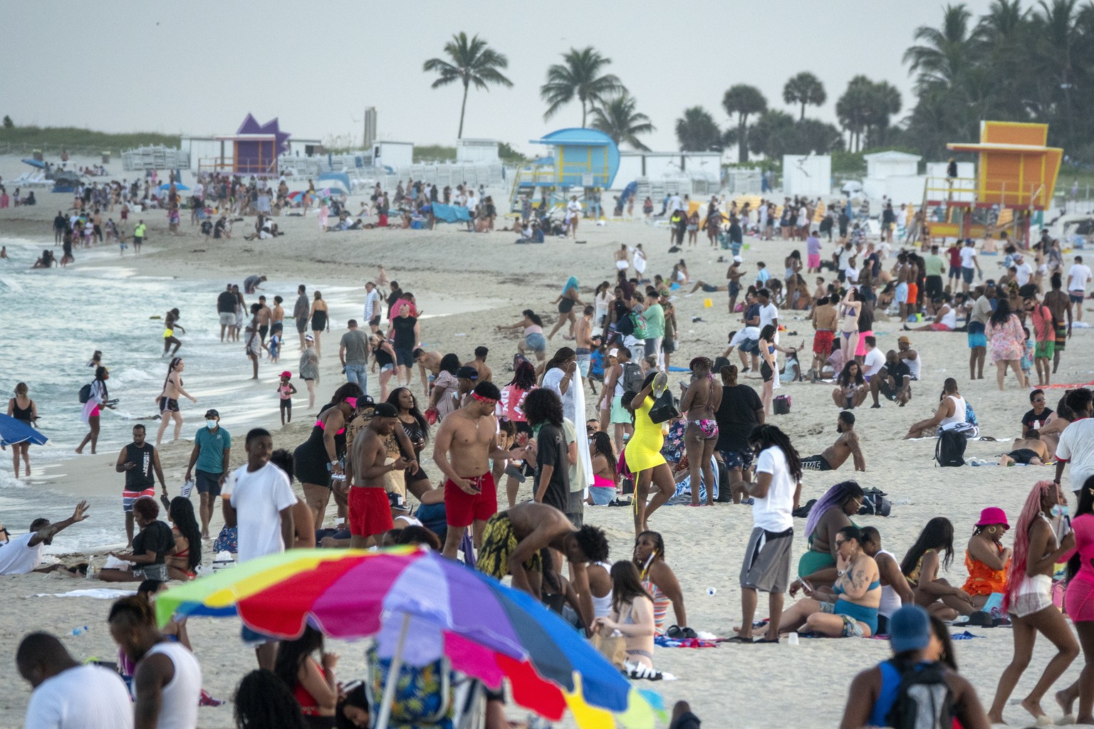 epa09087242 Large crowds of people gather during spring break, in Miami Beach, Florida, USA, 20 March 2021. Starting Saturday night, the city of Miami Beach is imposing a curfew for its entertainment  ...