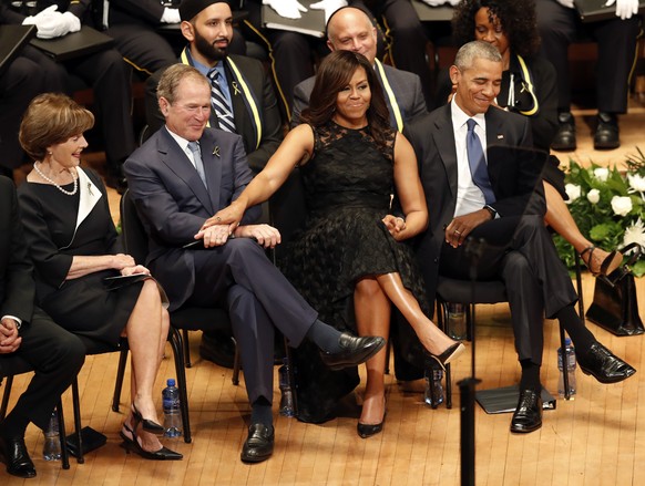 First lady Michelle Obama and President George W. Bush, flanked by President Barack Obama and former first lady Laura Bush, share a moment during a memorial service for five police officers were kille ...