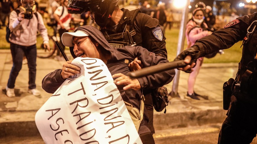 epa10367941 A policeman detains a woman who was demonstrating, outside the Palace of Justice in Lima, Peru, 15 December 2022. At least six protesters have died in the first 20 hours after the state of ...