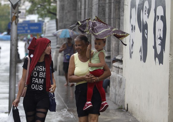 epa07079541 People cover themselves from the rain before the arrival of tropical storm Michael, Havana, Cuba, 08 October 2018. Cuban authorities decreed the first phase of the hurricanes protocol in f ...