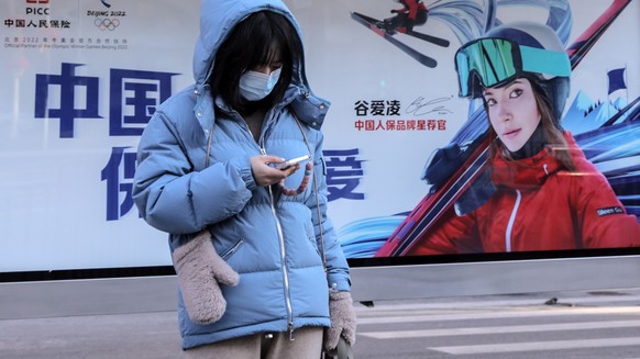 epa09761522 A woman stands near an advertising billboard depicting China&#039;s freestyle skier Gu Ailing Eileen at a bus station in Beijing, China, 16 February 2022. Team China Gu Ailing Eileen won t ...