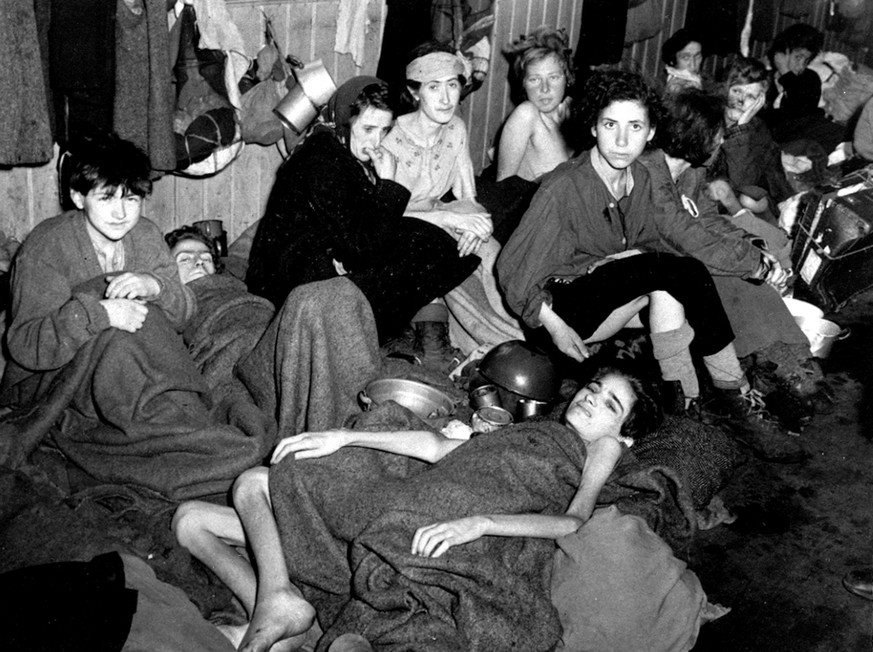 Women and children, some of over 40,000 concentration camp inmates liberated by the British, suffering from typhus, starvation and dysentary, huddle together in a barrack at Bergen-Belsen, Germany, in ...