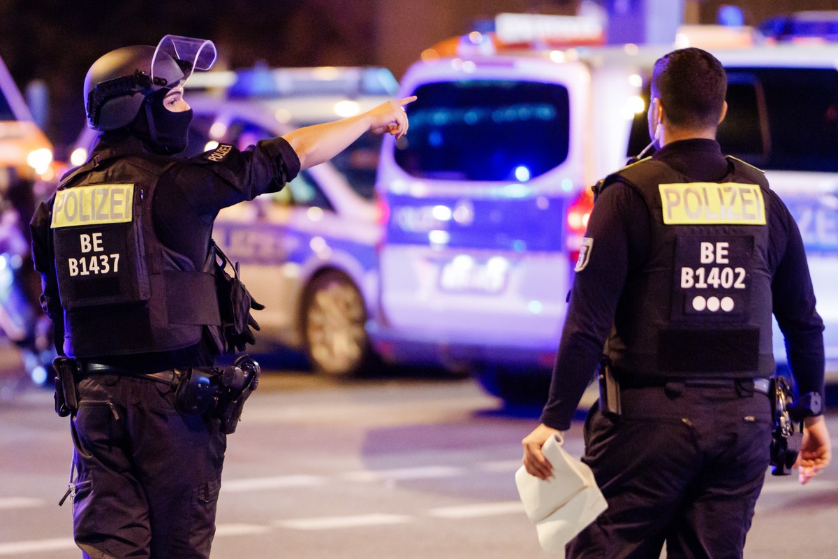 epa13133030 A police officer carrying a machine gun (L) and a colleague talk near the scene where several people were injured on the sideline of the Christopher Street Day (CSD) parade in Berlin, Germ ...