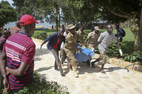 Ugandan police carry away a body of one of the victims of a boat which capsized in Lake Victoria near the capital, Kampala, Uganda, Sunday, Nov. 25, 2018. Police say dozens died when the boat, which w ...